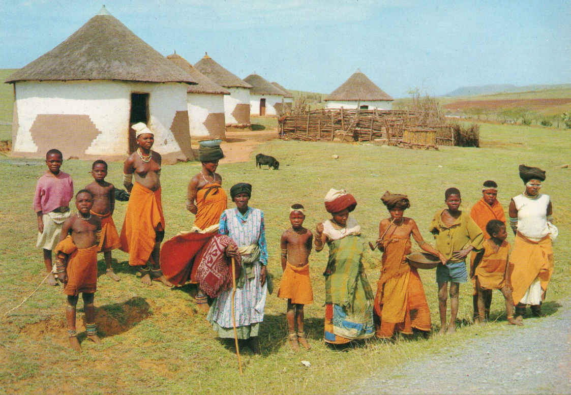 Transkei - Xhosa villagers - with some dressed in the traditional garb of Red Blanket and a woman smoking the characteristic long stemmed pipe